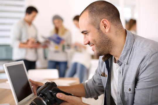 Cheerful reporter working in office on laptop