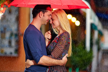 happy couple under the rain on evening street