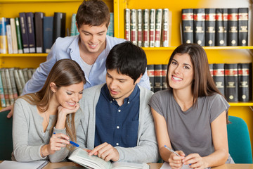 Female Student With Friends Reading Book In Library