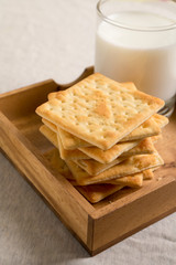 Crackers in wooden tray and a glass of milk