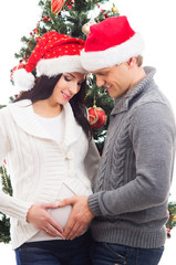 A pregnant woman and happy father decorating Christmas tree