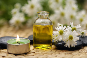 Bottle of massaging oil with gerbera over, stones ,candle