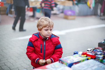 Beautiful toddler boy in red clothes on flea market.