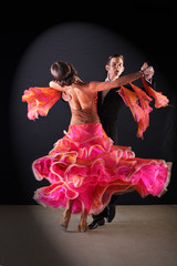 Latino dancers in ballroom against black background