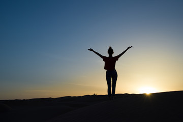 Fototapeta na wymiar Silhouette młoda kobieta z podniesionymi rękami o świcie
