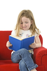 Mädchen ließt ein Buch im roten Sessel