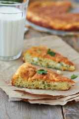 Two slices of pie with cheese and dill and glass of milk