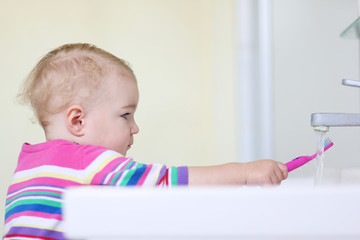 toddler girl cleaning tooth brush after brushing her teeth