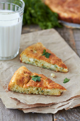 Two slices of pie with cheese and dill and glass of milk