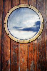 Porthole ship window on wooden doors, sky reflection