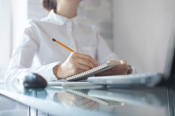 businesswoman writing with pencil on notepad in the office