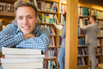 Male student with stack of books while others in background at l
