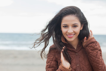 Cute smiling woman in stylish brown jacket on beach