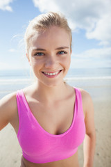 Smiling healthy woman in pink sports bra on beach