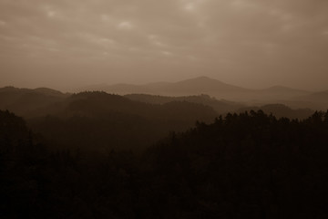 Trees and mountain range against cloudscape
