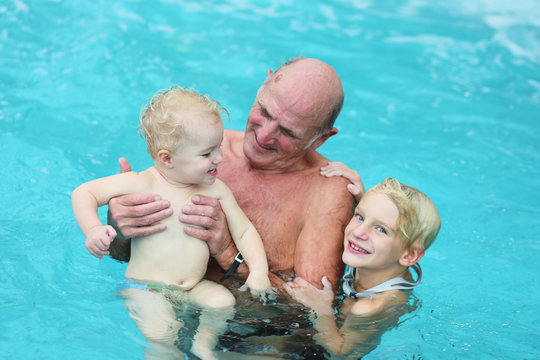 active grandfather with grandkids having fun in swimming pool