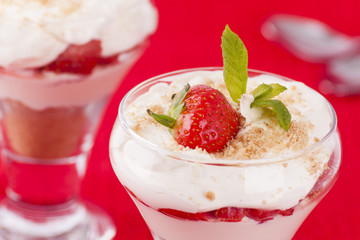 Two strawberry and cream desserts on red background