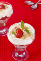 Two strawberry and cream desserts on red background