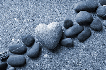 Grey stone in shape of heart, on sand background