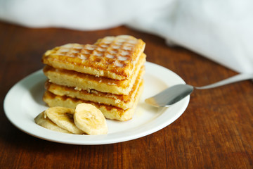 Sweet Belgium waffles with banana, on wooden table background