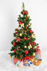Fototapeta na wymiar Decorated Christmas tree with gifts on grey wall background