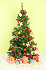 Decorated Christmas tree with gifts on green wall background