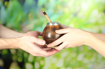 Woman hands giving calabash and bombilla with yerba mate,