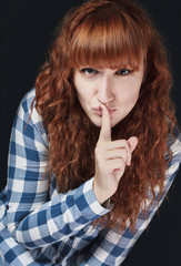 red-haired girl makes a gesture of silence