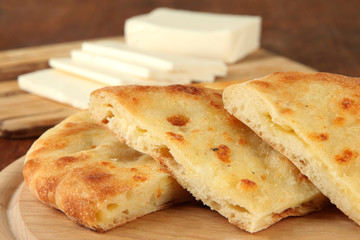 Pita breads with cheese on wooden stands close up