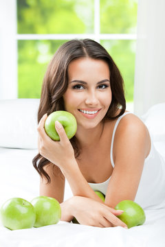Young happy smiling woman with apples, indoors