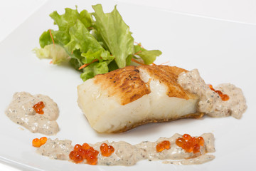 Fried halibut fillet with pepper sauce with salmon caviar