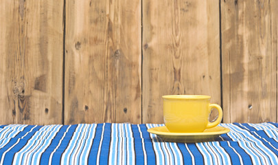 Yellow coffee cup and saucer on a colorful tablecloth