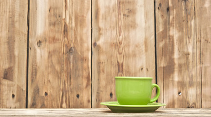 green coffee cup on wooden tabletop against grunge wooden backgr