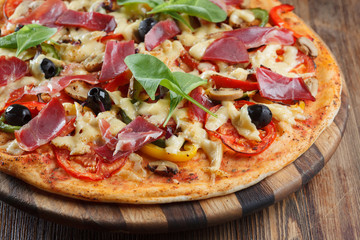 Pizza with hum, cheese, tomato and pepper on wooden table