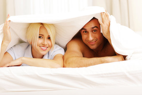 Happy young couple lying on the bed at home