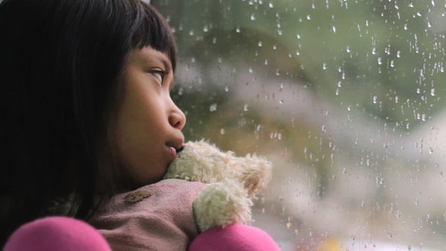 Depressed Little Asian Girl By The Window