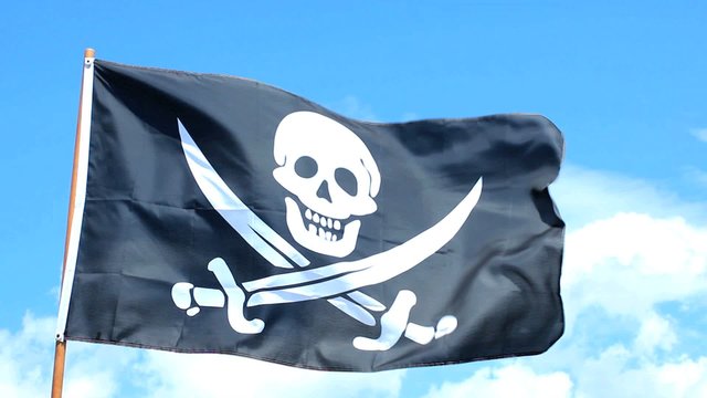 Jolly Roger pirate flag waving over a blue sky.