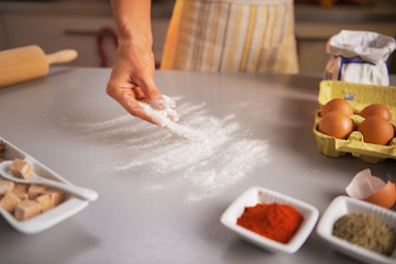 Obraz na płótnie Canvas Motion blurred closeup on housewife sprinkling flour on table