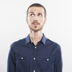 Closeup of young man looking up thinking on white background