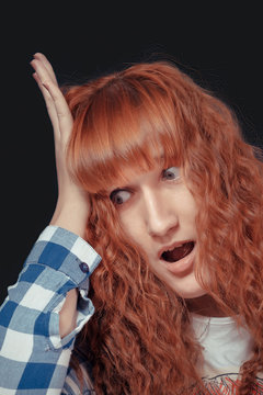 red-haired girl shows emotion on a dark background