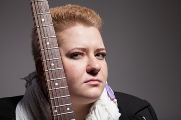 Chubby woman with short hair holding guitar