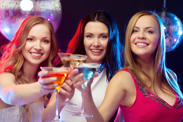 three smiling women with cocktails and disco ball
