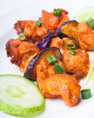 Grilled chicken on a white plate with vegetables on background.
