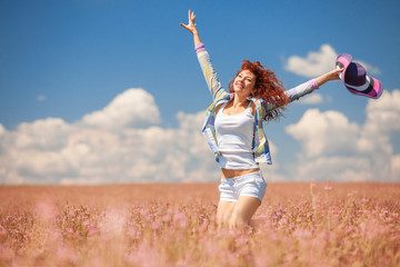 Cute woman running in the field with flowers