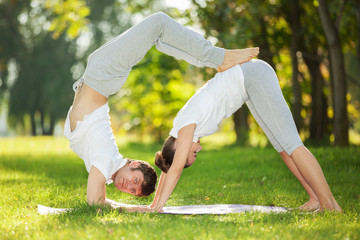 Couple Yoga, man and woman doing yoga exercises in the park