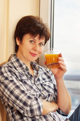 Woman with a glass of juice sitting near the window