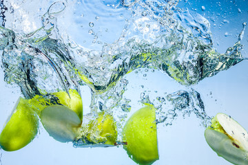 Green apples. Fruits fall deeply under water with a big splash