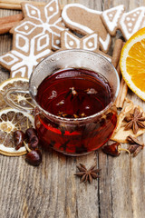 Glass of hot steaming tea among christmas decorations on wooden