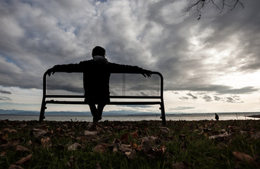 man sitting on bench at lake constance