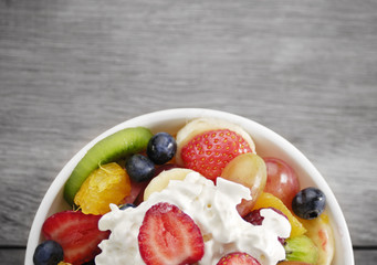 Sweet tasty fruit salad in the bowl with whipped cream © i_tkach